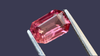 Elegant pink spinel gemstone with slight visible inclusions, expertly cut in an emerald shape, set against a deep slate blue background. Ideal for bespoke jewellery designs and ethically sourced from Myanmar.