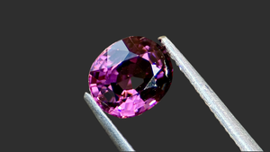 Natural Mogok Spinel gemstone with deep purple hues, oval cut, elegantly displayed on a luxurious dark charcoal grey background. Perfect for high-end bespoke jewellery, ethically sourced from Myanmar. Exquisite Spinel for custom fine jewellery designs.